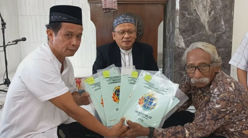 Masruhan (baju batik) serahkan sertifikat tanahnya kepada ketua PD Muhammadiyah Jombang Dr Abdul Malik (baju putih) disaksikan oleh Ketua Majelis Tabligh PP Muhammadiyah Ust Fathurrohman Kamal (tengah)